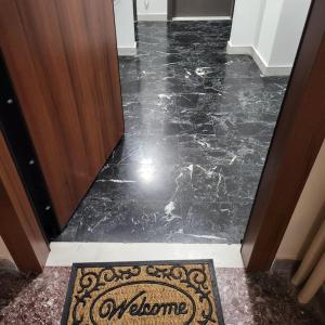 a hallway with a black marble floor with a welcome mat at GREAT APARTMENT IN VERIA in Veria