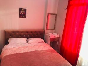 a bedroom with a bed with red curtains at Rezidenca SHOPI Apartments in Elbasan
