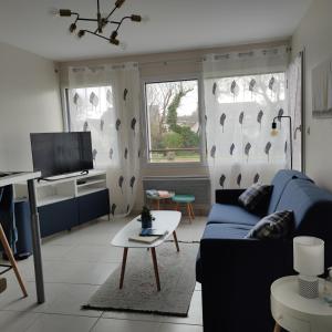 sala de estar con sofá azul y mesa en CHARMANT APPARTEMENT 3 étoiles classé BORD DE MER Travel Award 2024, en Plougonvelin