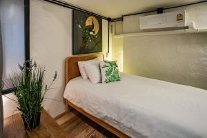 a small bedroom with a bed and a plant at Luxury Industrial Flat in the Heart of Chiang Mai in Chiang Mai