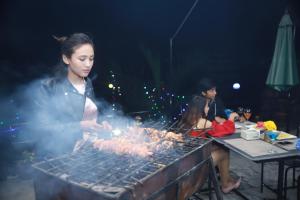 a woman is cooking meat on a grill at Rock Garden Resort in Pokhara +37 photos