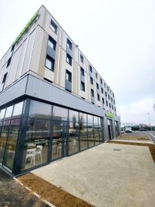 un grand bâtiment avec des fenêtres en verre et une table dans l'établissement B&B HOTEL Dreux Nord, à Dreux