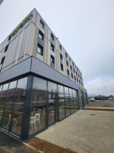 un edificio con muchas ventanas y mesas en B&B HOTEL Dreux Nord, en Dreux