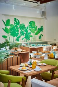 a restaurant with wooden tables and green chairs at Hotel Colonial in Colonia Sant Jordi