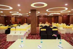 una sala conferenze con tavoli e sedie bianchi e gialli di Regenta Inn Greater Noida, 15 Mins to India Expo Mart a Greater Noida
