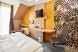 a hotel room with a bed and a desk and a tv at Flair Hotel Zum Schwarzen Reiter in Horgau