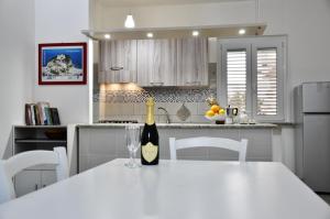a white kitchen with a bottle of wine on a table at Sapore di mare Home in Santa Domenica