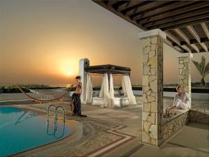 a man standing next to a pool with a hammock at Aldemar Olympian Village in Olympia