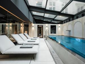 an indoor pool with white chairs and a swimming pool at The Amauris Vienna - Relais & Châteaux in Vienna