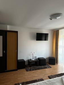 een woonkamer met 2 stoelen en een televisie aan de muur bij Pensiunea Andra in Timişoara