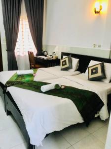 a bedroom with two beds and a table and a window at Siemreap Nitnit Boutique in Phumĭ Kngan Pông
