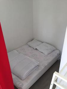 Bett mit weißer Bettwäsche und Kissen in einem Zimmer in der Unterkunft Beau 2 pièces proche plage et commerces in Le Pouliguen
