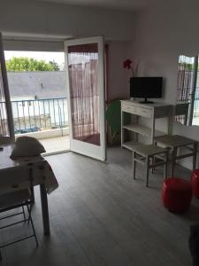 a living room with a television and a table and chairs at Beau 2 pièces proche plage et commerces in Le Pouliguen