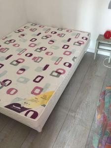 ein Bett mit einer Bettdecke auf einem Holzboden in der Unterkunft Beau 2 pièces proche plage et commerces in Le Pouliguen