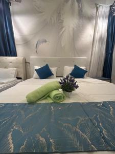 古晉的住宿－P' Residence Condo, Batu Kawa, Kuching，一张带绿色枕头和鲜花的床