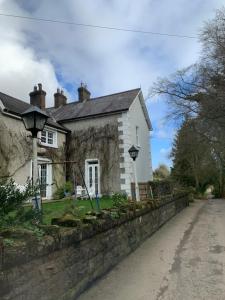 a white house with a stone wall next to a street at Tullyard House 