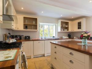 cocina con armarios blancos y encimera en Almsbury Farmhouse, en Winchcombe