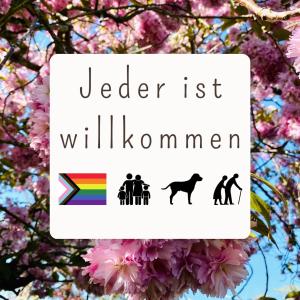a sign with a rainbow and a group of people and a tree at Feriengut Neuhof in Fehmarn