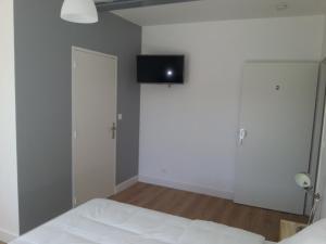 een slaapkamer met een bed en een flatscreen-tv aan de muur bij Bull'it Hotel in Saint-Genis-Laval