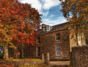 uma antiga casa de pedra com folhas e árvores de Outono em The Old Convent Holiday Apartments em Fort Augustus