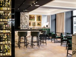 um bar com cadeiras verdes e garrafas de vinho em The Amauris Vienna - Relais & Châteaux em Viena