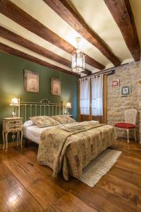 a bedroom with a large bed and a stone wall at La Posadica Casa Aldabe in San Martín de Unx