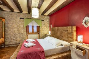 1 dormitorio con paredes rojas y 1 cama con toallas. en La Posadica Casa Aldabe, en San Martín de Unx