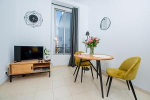 salon ze stołem, krzesłami i telewizorem w obiekcie Marceau Central Flat w Nicei