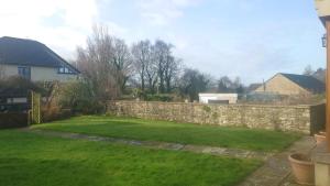 um quintal com uma parede de pedra e um quintal com relva em Rosebank Lodge em High Bentham