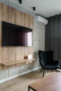 a black chair and a television on a wall at RentPlanet - Kępa Mieszczańska in Wrocław