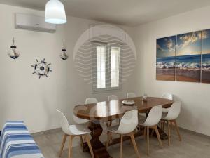 a dining room with a wooden table and white chairs at Villa Alysa - spiaggia a 400m in Porto Cesareo