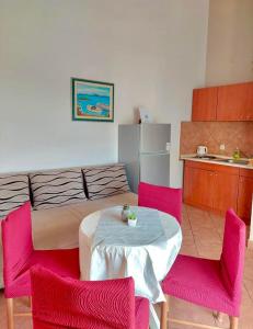 een kamer met een tafel en twee roze stoelen bij Grgo Apartments in Drage