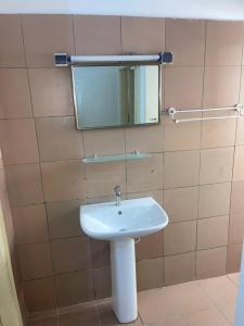 bagno con lavandino bianco e specchio di KADIDJA APARTMENTS & SUITES Akodessewa a Lomé