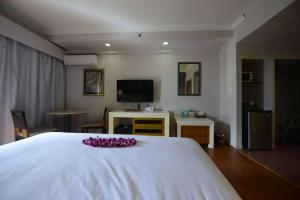 a bedroom with a white bed with purple flowers on it at Days Inn Guam - Tamuning in Tamuning