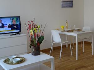 a living room with a white table and a tv at Villa Médicis Versailles Saint-Cyr-l'Ecole in Saint-Cyr-lʼÉcole