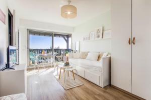 a white living room with a couch and a balcony at Appartement cosy avec vue imprenable sur Cabourg - accès direct plage - proche centre ville in Cabourg