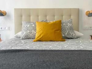 Cama con almohada amarilla y algunas almohadas en Apartamento Ayla Camino de Santiago, en Pamplona
