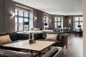 Best Western Plus Hotel Kronjylland في راندرس: غرفة معيشة مع كنب وطاولات وبار