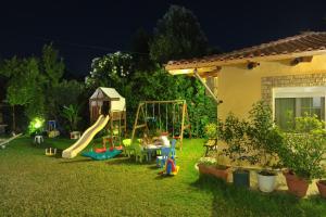 un patio trasero con un tobogán y un parque infantil por la noche en Galazia Akti, en Agios Nikolaos