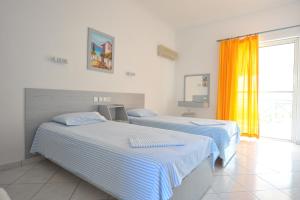 2 camas en una habitación blanca con ventana en Galazia Akti, en Agios Nikolaos