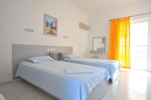 two beds in a white room with a window at Galazia Akti in Agios Nikolaos