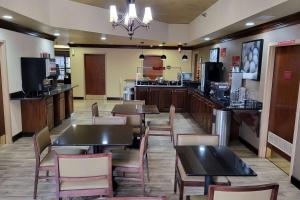 a restaurant with tables and chairs and a bar at Wingate by Wyndham Greensboro-Coliseum in Greensboro