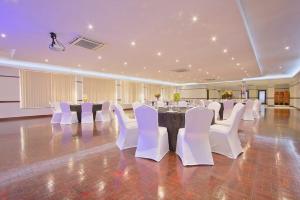 um salão de banquetes com cadeiras brancas e uma mesa em THE Pretoria Hotel em Pretoria