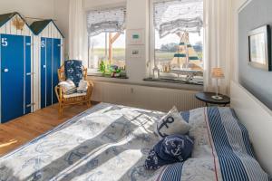 a bedroom with a bed and a chair and windows at Friesenbiene in Dornumersiel