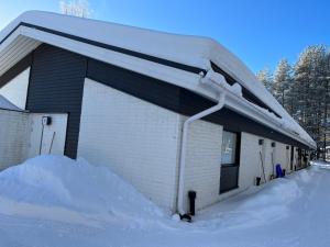 a snow covered building with a snow pile next to it at Townhouse with SAUNA&FREE PARKING close to Santa Claus Village & Santa Park in Rovaniemi