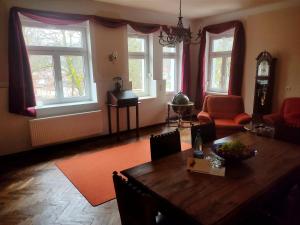 een woonkamer met een tafel, stoelen en ramen bij Parkvilla Köhler in Zella-Mehlis