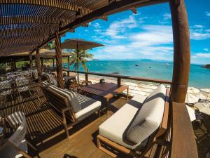een terras met stoelen en een tafel en de oceaan bij Hotel La Forêt & Beach Club in Búzios