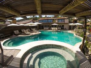 une grande piscine avec des chaises et des parasols dans l'établissement Hotel La Forêt & Beach Club, à Búzios