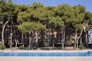 un hotel con árboles y una piscina en AT046 Els Pins, 1ra línea de la playa, piscina, airco, aparcamiento, en Torredembarra