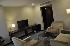 uma sala de estar com 2 cadeiras e uma televisão de ecrã plano em Happy Inn Gebze Hotel em Cocaeli